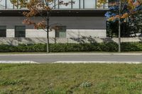 a street corner and an empty sidewalk in front of a white building with glass windows