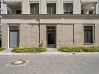 a courtyard and entry to the apartment building with a clock on a wall and small planters outside