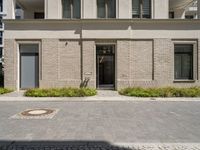 a courtyard and entry to the apartment building with a clock on a wall and small planters outside