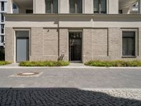 a courtyard and entry to the apartment building with a clock on a wall and small planters outside