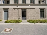 a courtyard and entry to the apartment building with a clock on a wall and small planters outside