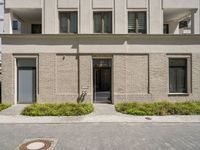 a courtyard and entry to the apartment building with a clock on a wall and small planters outside