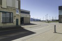 a empty street outside of a brick building with a store sign and parking lot in the background