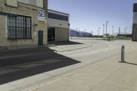 a empty street outside of a brick building with a store sign and parking lot in the background