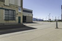 a empty street outside of a brick building with a store sign and parking lot in the background