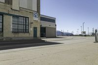 a empty street outside of a brick building with a store sign and parking lot in the background