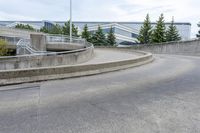 a long curved sidewalk is at the top of an outdoor walkway area with stairs leading to an office building