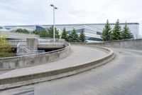 a long curved sidewalk is at the top of an outdoor walkway area with stairs leading to an office building