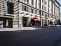 the street is empty in a city with buildings on the side and two pedestrians walking down the road