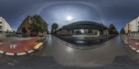 a panoramic photo of the intersection in a city street as a traffic light shines