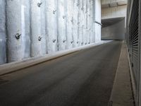 a narrow street is lined by concrete wallpaper and security bars on both sides of the road