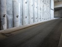 a narrow street is lined by concrete wallpaper and security bars on both sides of the road