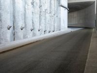 a narrow street is lined by concrete wallpaper and security bars on both sides of the road