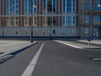 a street light next to an empty road in front of a building with a traffic light on top of it