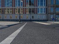 a street light next to an empty road in front of a building with a traffic light on top of it