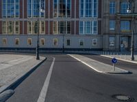 a street light next to an empty road in front of a building with a traffic light on top of it