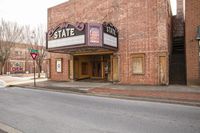 the state theatre sign is on a side walk next to the sidewalk of this town