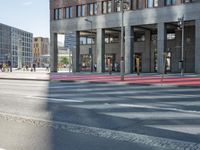 an urban road and a building, with the reflection of a woman in the car