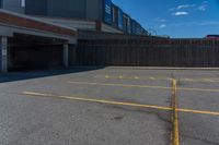 an empty parking space with yellow lines painted down the middle of it and two garages on top