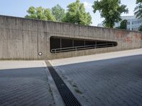 a road in the middle of a large concrete building and trees along side with a metal guardrail