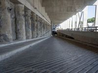 there is only one skateboard under a bridge that spans the street, which also has stairs,