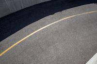 a road with a concrete wall and two metal circular ball lights on the side of the road