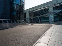 some concrete walkway next to a tall building with an opening door in the middle of the road