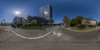 a view of a street intersection with a arrow sign and buildings in the background as shown on this fish eye lens