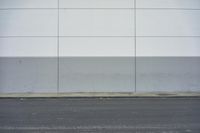 a white building on the street next to the road with a white line painted on the side