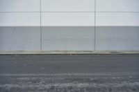 a white building on the street next to the road with a white line painted on the side