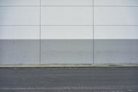 a white building on the street next to the road with a white line painted on the side