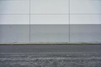 a white building on the street next to the road with a white line painted on the side