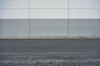 a white building on the street next to the road with a white line painted on the side