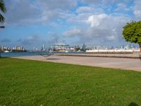 a park with a park bench and water next to it and cityscape in the background