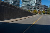 a street near some tall buildings and a black fence with yellow striping on the street