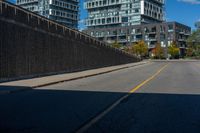 a street near some tall buildings and a black fence with yellow striping on the street