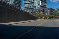 a street near some tall buildings and a black fence with yellow striping on the street