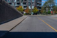 this is an empty street with cars parked along it and a wall beside it to the side