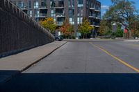 this is an empty street with cars parked along it and a wall beside it to the side