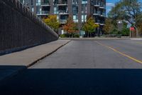 this is an empty street with cars parked along it and a wall beside it to the side