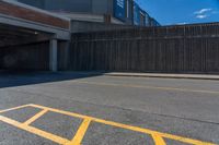 the shadow of a parking lot is on a paved street below a building with a ramp