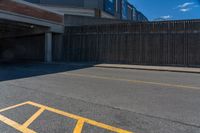 the shadow of a parking lot is on a paved street below a building with a ramp