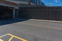 the shadow of a parking lot is on a paved street below a building with a ramp