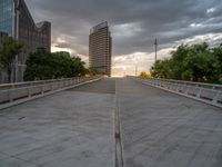 there is a large cement bridge over the road on a cloudy day with tall buildings in the background