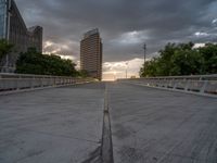 there is a large cement bridge over the road on a cloudy day with tall buildings in the background