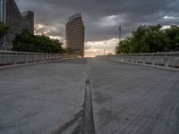 there is a large cement bridge over the road on a cloudy day with tall buildings in the background