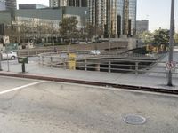 cars driving in between road barriers on the side of street at city skyline with a building in background