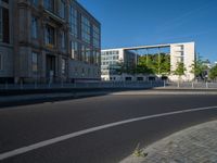 a street light next to an empty road in front of a building with a traffic light on top of it