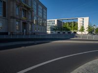 a street light next to an empty road in front of a building with a traffic light on top of it