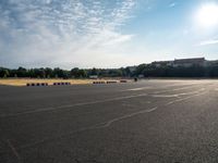 an empty parking lot filled with white, black and red stripes on the pavement with a city in the background